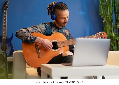 Young Man Sitting In His Room And Watching Guitar Tutorial On Laptop