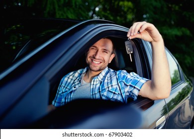 Young Man Sitting Inside New Car With Keys. Smiling