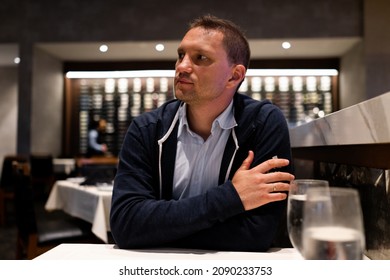 Young Man Sitting Inside Restaurant For Dinner With Dim Lights Dark Atmosphere Looking Waiting For Food Waiter Or Date With Two Glasses Of Water