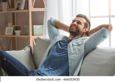 Young Man Sitting On Coach Rest At Home