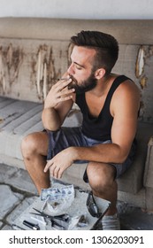 Young Man Sitting On A Couch, Relaxing And Smoking Pot 