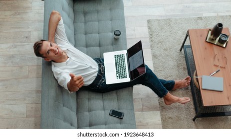 Young Man Sitting On The Couch And Giving A Thumbs Up.