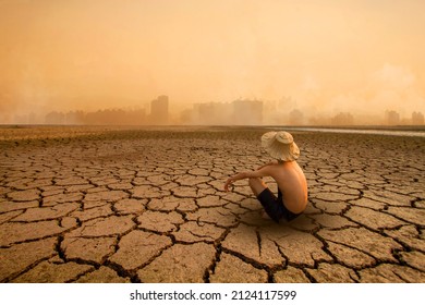 Young man sitting on drying river and looking to polluted city with smoke of co2, carbon dioxide on background. Metaphoric of Environment damage, Climate change and pollution.