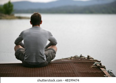 Young man sitting on a pontoon by a lake