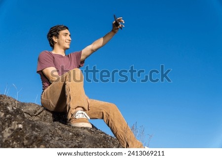 young man sitting on a rock, capturing a moment with a smile for the camera.