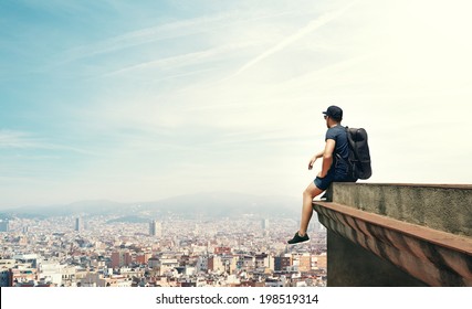 Young man sitting on a roof and looking city - Powered by Shutterstock