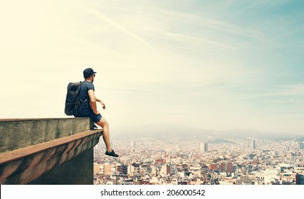 Young man is sitting on a roof and looking city - Powered by Shutterstock