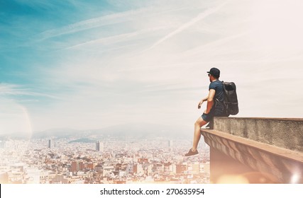 Young man is sitting on a roof and looking at the city - Powered by Shutterstock