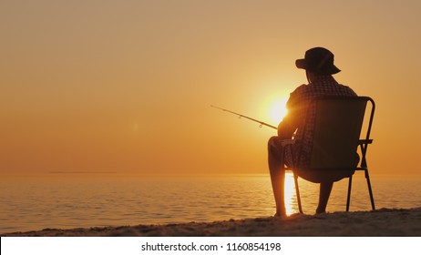 A young man is sitting on the seashore, fishing. Relaxing in the open air