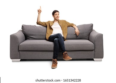 Young Man Sitting On A Sofa And Pointing Up Isolated On White Background