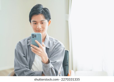 Young man sitting on a sofa operating a smartphone - Powered by Shutterstock