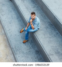 Young man sitting on stairs alone on street high angle view. Social distance in empty city