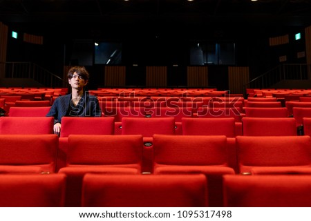 Young man sitting on theater seat.