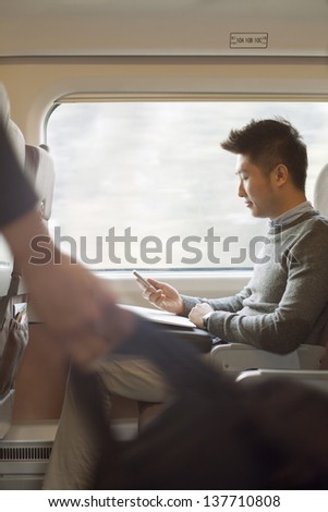 Young man sitting on a train using his phone
