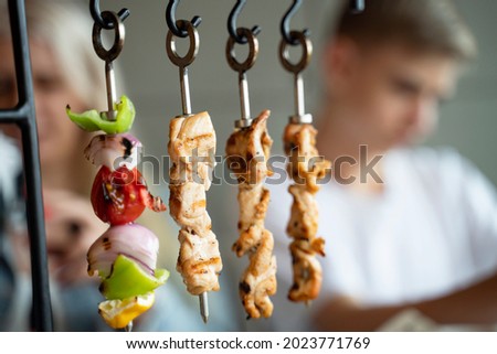 Young man sitting in a restaurant or outdoor cafe he ordered vegetable and chicken skewers on skewers. 