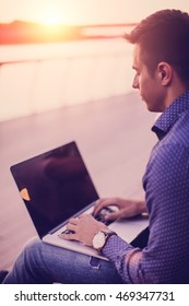 Young Man Sitting At The Stairs And Using Laptop. Back View