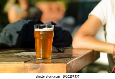 Young Man Sitting At A Table With A Glass Of Craft Blonde Beer, Outdoor Bar Natural Scene