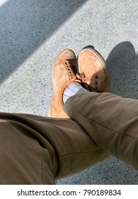 A Young Man Is Sitting And Wearing Proper Attire With Brown Shoes, Grey Socks And Brown Pant