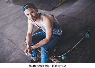 Young man skateboarder. Male teenager with longboard in skatepark.