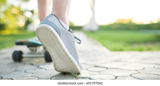 Young Man Skateboarder On Skateboard At Sunset City Park, Full Length Shot With Copy Space Close Up On Shoe