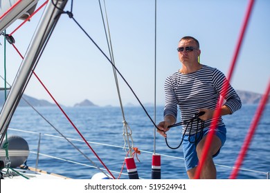 Young Man Skipper At His Sail Boat, Controls Ship During Sea Yacht Race. Luxery Vacations, Sailing, Adventure, Travel.