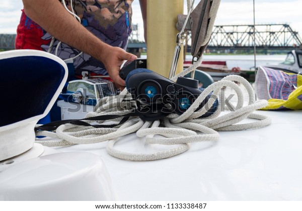 Young man skipper sets sail on\
a sailing yacht boat with through binoculars and bridge\
view