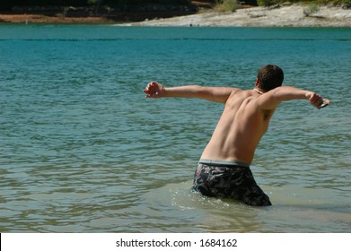 Young Man Skipping Rocks At The Lake