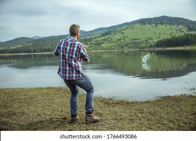 A Young Man Skipping A Stone On Lake Water