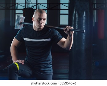 Young Man With A Sledge Hammer On The Shoulder Of Sports Training In The Gym. Crossfit Workout.