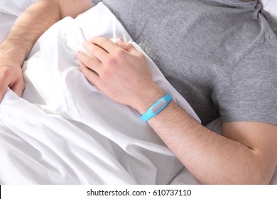 Junge Männer mit Schlaftracker, die zu Hause im Bett liegen, Nahaufnahme