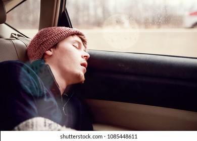 Young Man Sleeping In The Backseat Of A Car On A Trip