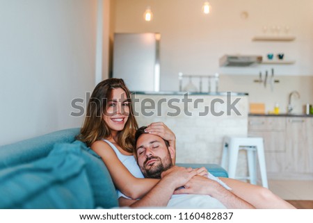 Young man sleeping in girfriend's lap. Woman looking at camera. Close-up.