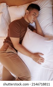 Young Man Sleeping With Pillow Between Legs, Which Keeps His Pelvis Neutral And Prevents Spine From Rotating During Night