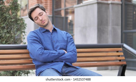 Young Man Sleeping while Sitting Outdoor on Bench
