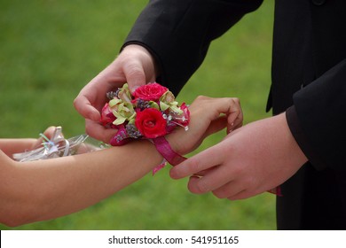 Young Man Slides Wrist Corsage Onto Prom Date