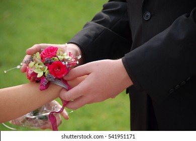 Young Man Slides Wrist Corsage Onto Prom Date