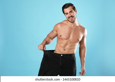 Young man with slim body in old big size jeans on light blue background - Shutterstock ID 1465100810