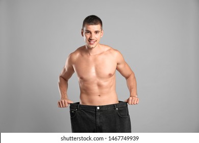 Young man with slim body in old big size jeans on grey background - Shutterstock ID 1467749939
