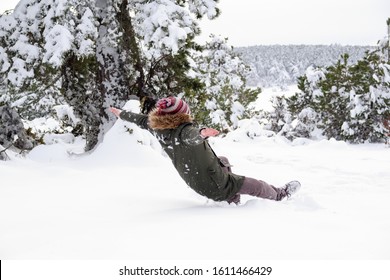 Young Man Slips, Lost His Balance And Fall Back During A Walk At Forest In Winter. Freeze Frame While Slide Down To The Snow. Falling On Snow In Winter.