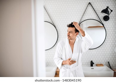 Young Man With Smartphone In The Bathroom In The Morning.