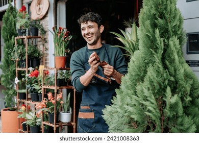 Young man smiles in plant store.
concept: small plant and nursery business.