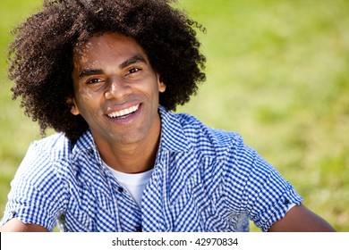 Young man smiling at camera in a park. Horizontally framed shot. - Powered by Shutterstock