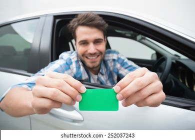 Young Man Smiling And Holding Card In His Car