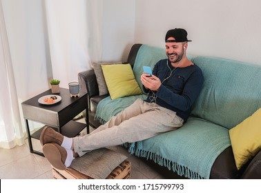 Young Man Smiling And Talking With Family On A Video Call - Home Isolation For The Coronavirus Crisis - Italian Man Laughing With Smartphone In His Hands