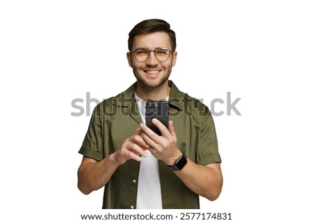 Young man smiling while using a smartphone in a casual outfit against a plain background