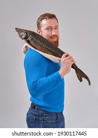 Young Man With A Smoked Sturgeon In His Hands. On A White Background Of A Cyclorama, Studio Photo