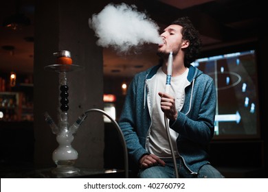 young man smokes a fragrant oriental hookah