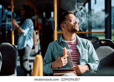 Joven fumando cigarrillos electrónicos en el transporte público.