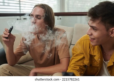 Young man smoking vape when spending time with best friend