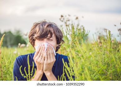Young man sneezes because of an allergy to ragweed - Shutterstock ID 1039352290